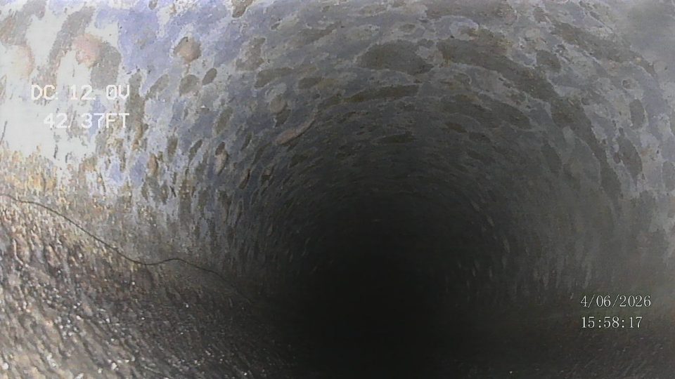 Sewer camera footage looking down the inside of a drain pipe, showing the on-screen distance counter and inspection date/time stamp